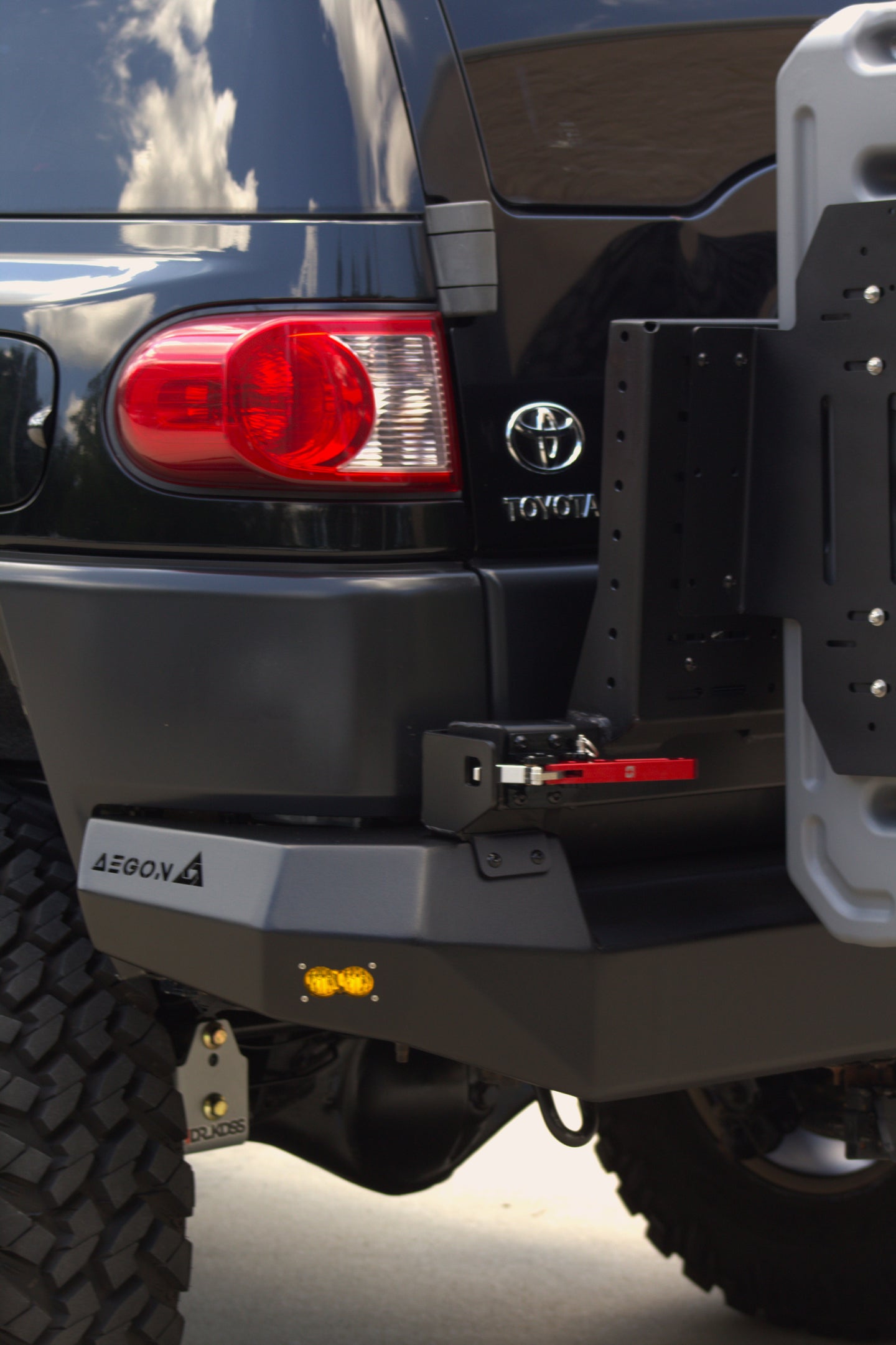 AEGON steel rear bumper installed on a Toyota FJ Cruiser, shown next to the factory Toyota badge and taillight
