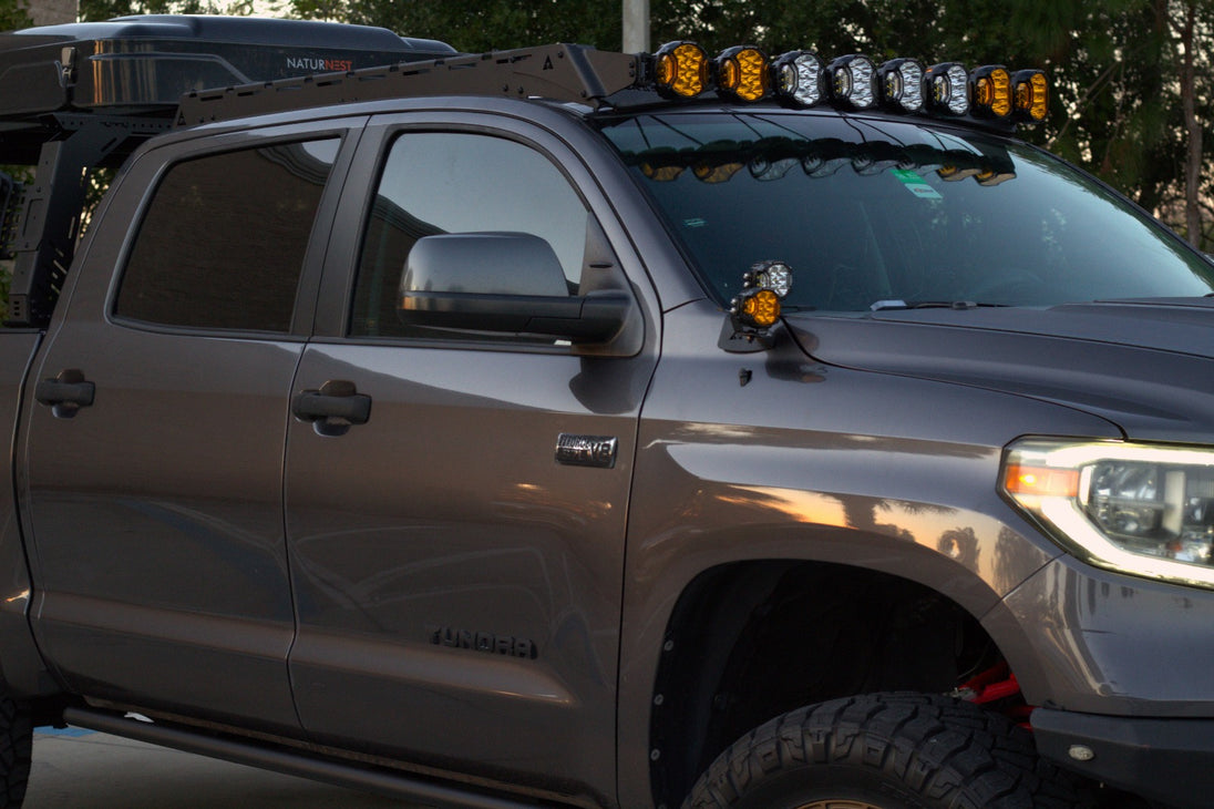 Toyota Tundra with side hood lights illuminated on a dark trail for maximum visibility.