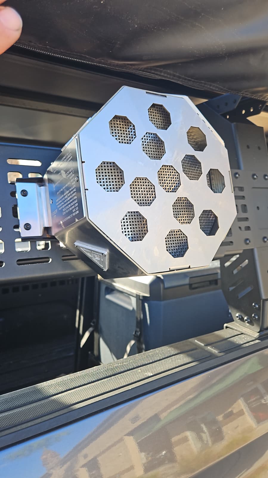 Propane fire pit mounted to a truck bed MOLLE panel for secure off-road storage.