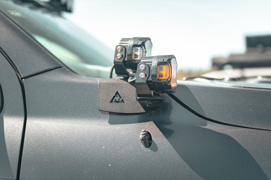 Pair of black steel AEGON hood side light mount brackets for 2007-2021 Toyota Tundra.